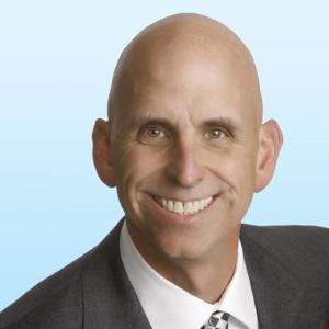 A person in a suit smiling in a professional headshot.