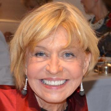 A smiling woman wearing earrings and a red top.