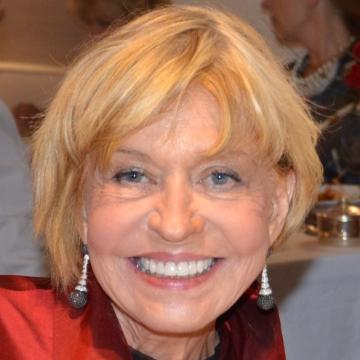 A smiling woman wearing earrings and a red top.