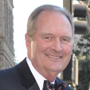 A man in formal attire, smiling outdoors.