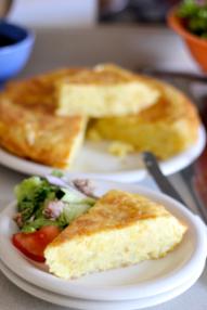 Sliced tortilla de patatas served on a plate with vegetables.