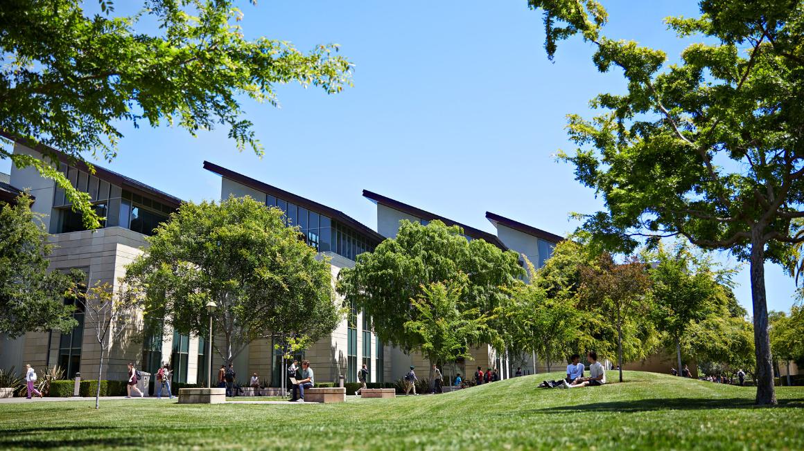 Students lounging and walking outside of a building on campus. 