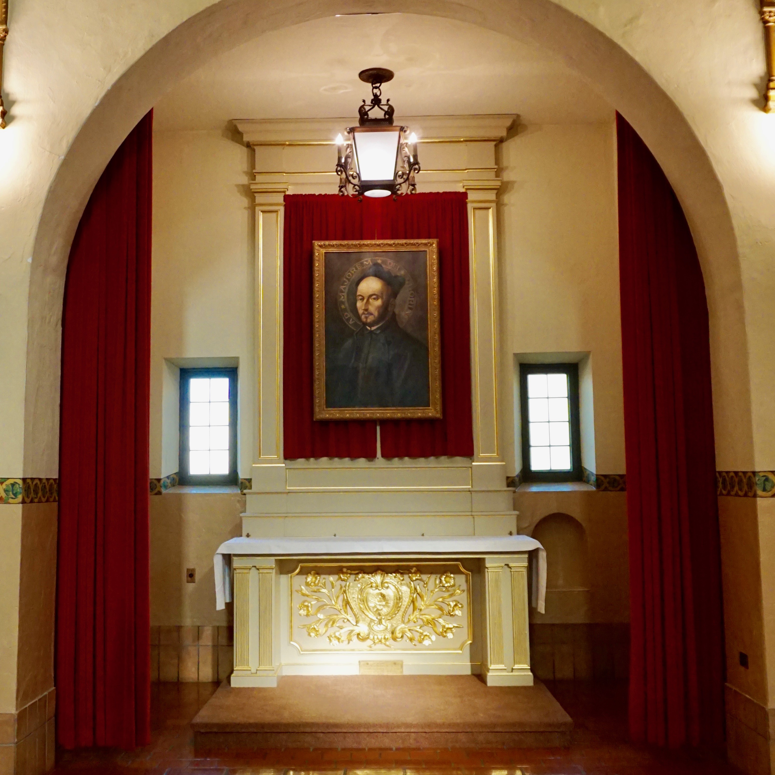 St. Ignatius Side Chapel with altar, painting, and red curtains.