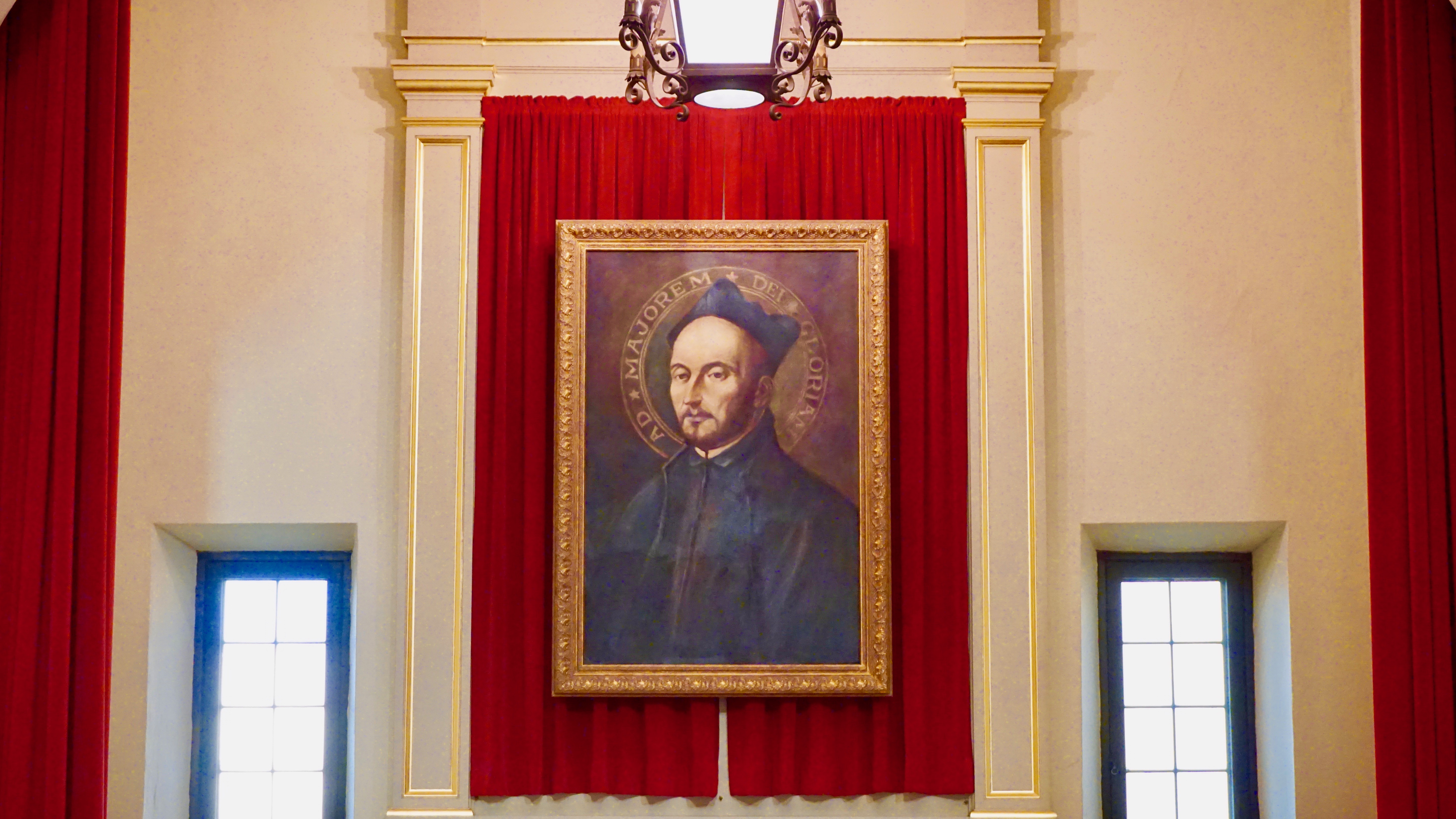 A framed painting of a person with a red background, titled St. Ignatius Painting.