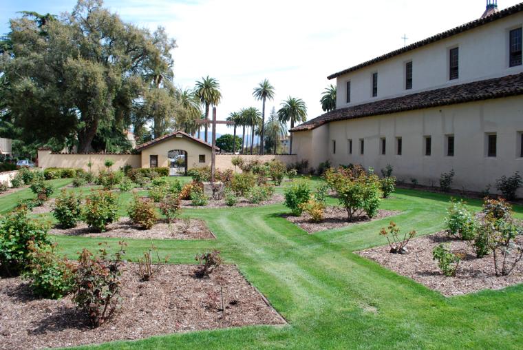 Rose garden with cemetery overlook beside building.