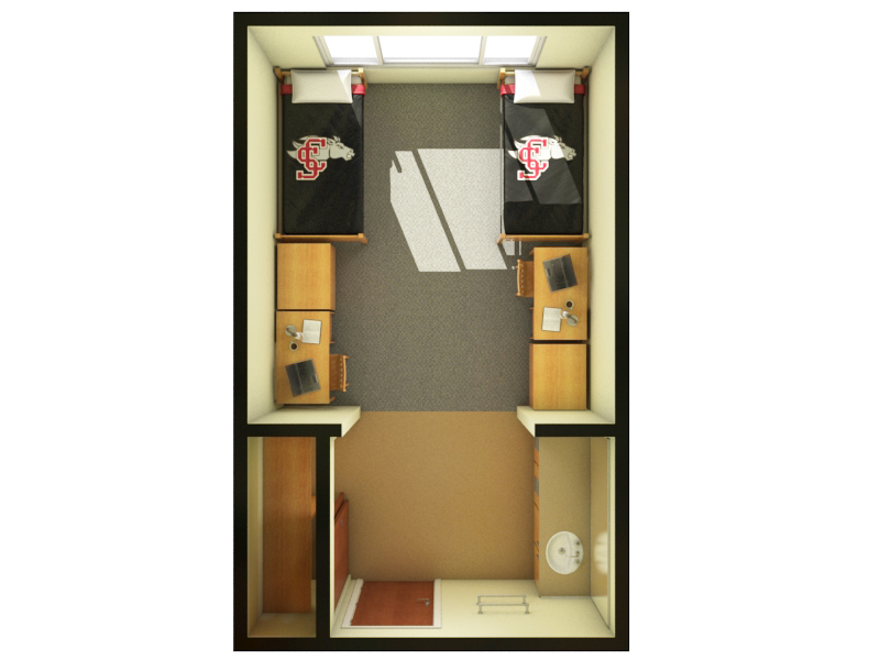Dorm room with two beds, desks, and storage cabinets.