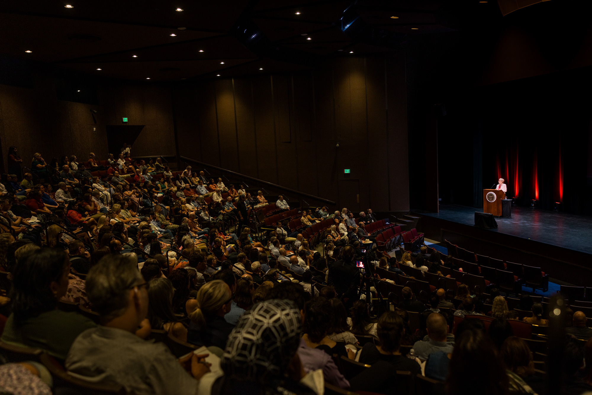 Santa Clara University President Julie Sullivan addresses a full auditorium from the stage during campus convocation.