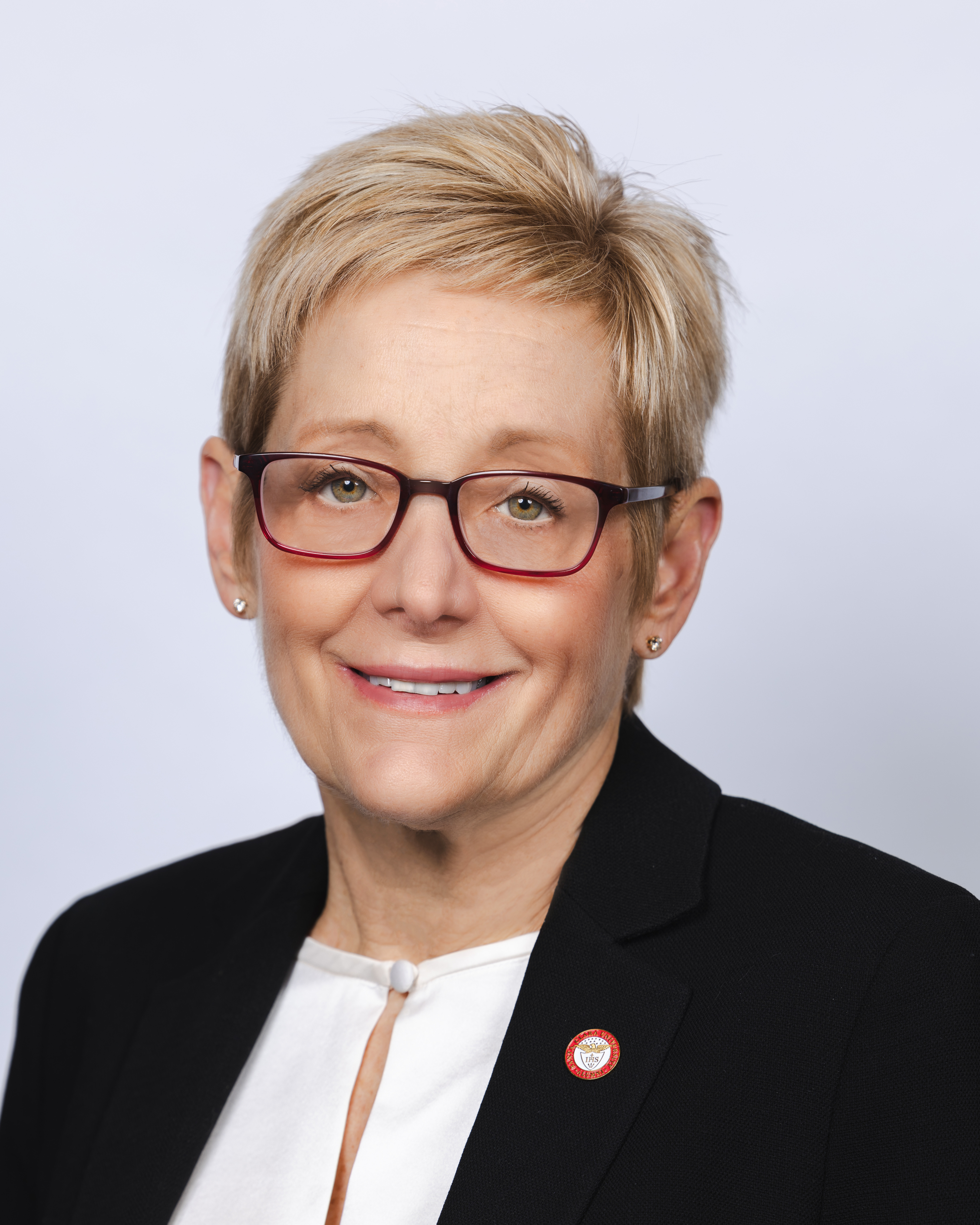 Head Shot of smiling woman with short blond hair and red glasses