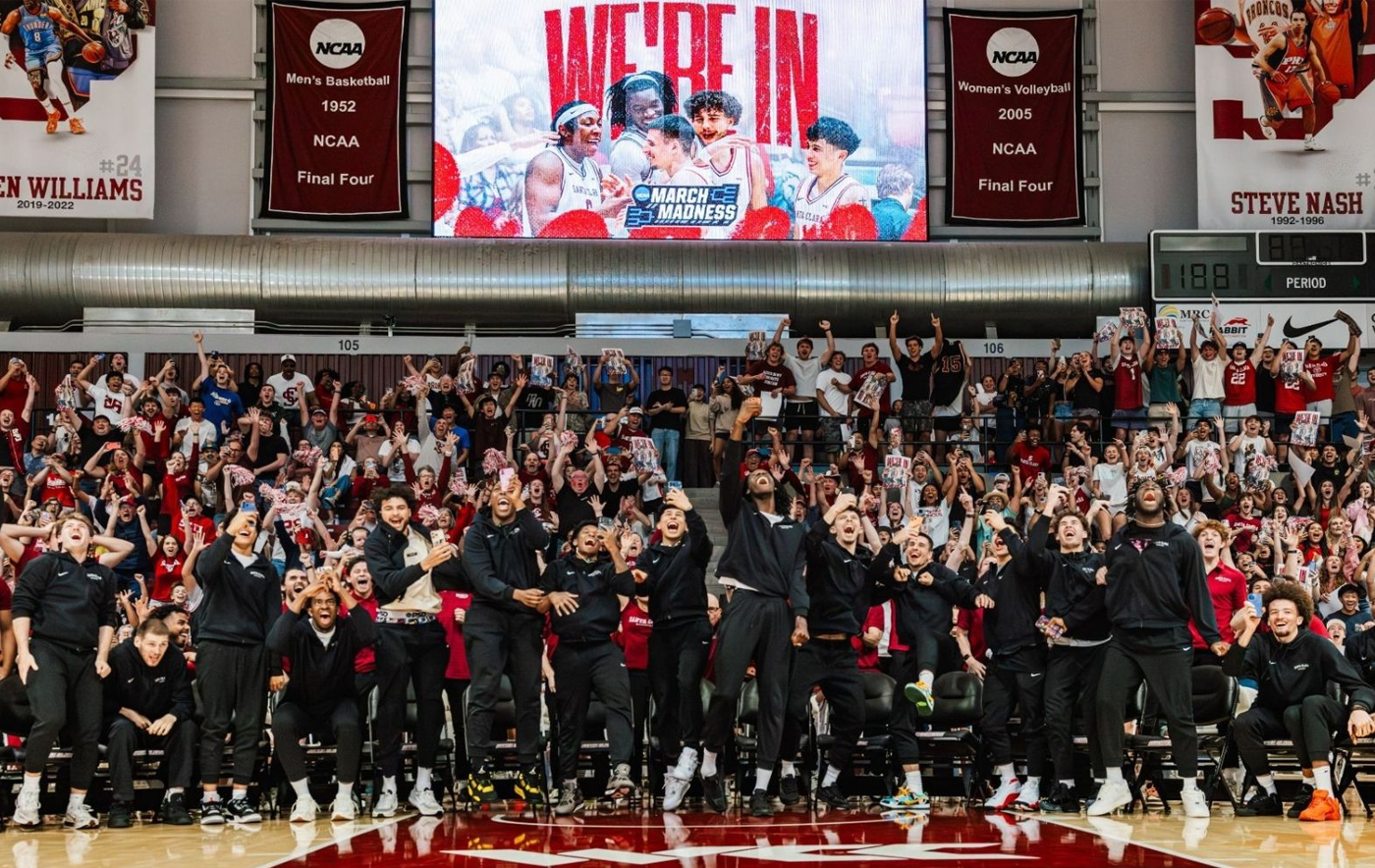 Santa Clara men’s basketball players and fans celebrate in Leavey Center as a video board announces the team has made the NCAA March Madness tournament.