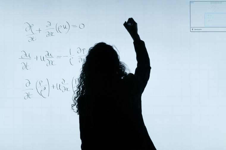 Silhouette of an instructor writing on a whiteboard. 