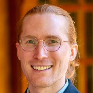 man in glasses smiles at camera