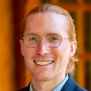 man in glasses smiles at camera 