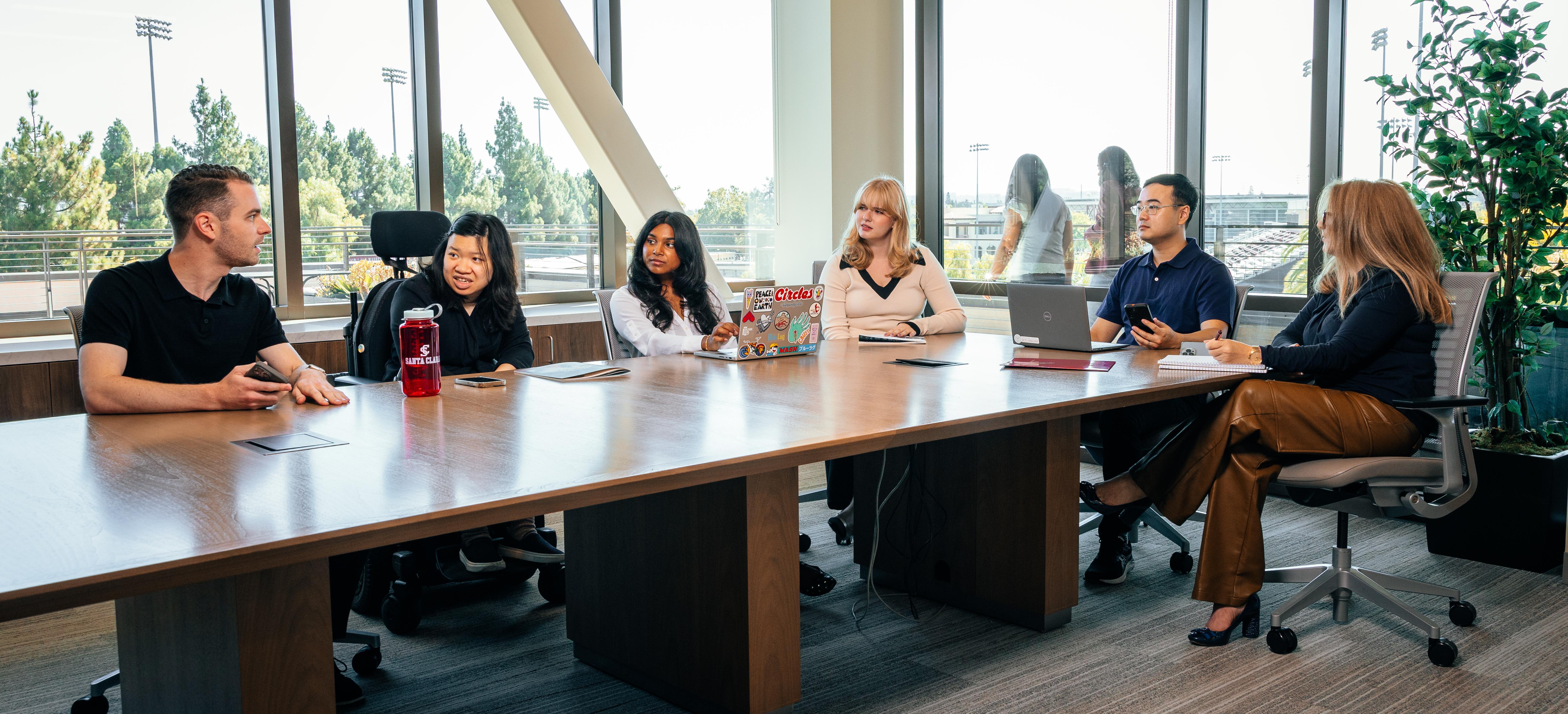 students at a conference table with faculty 