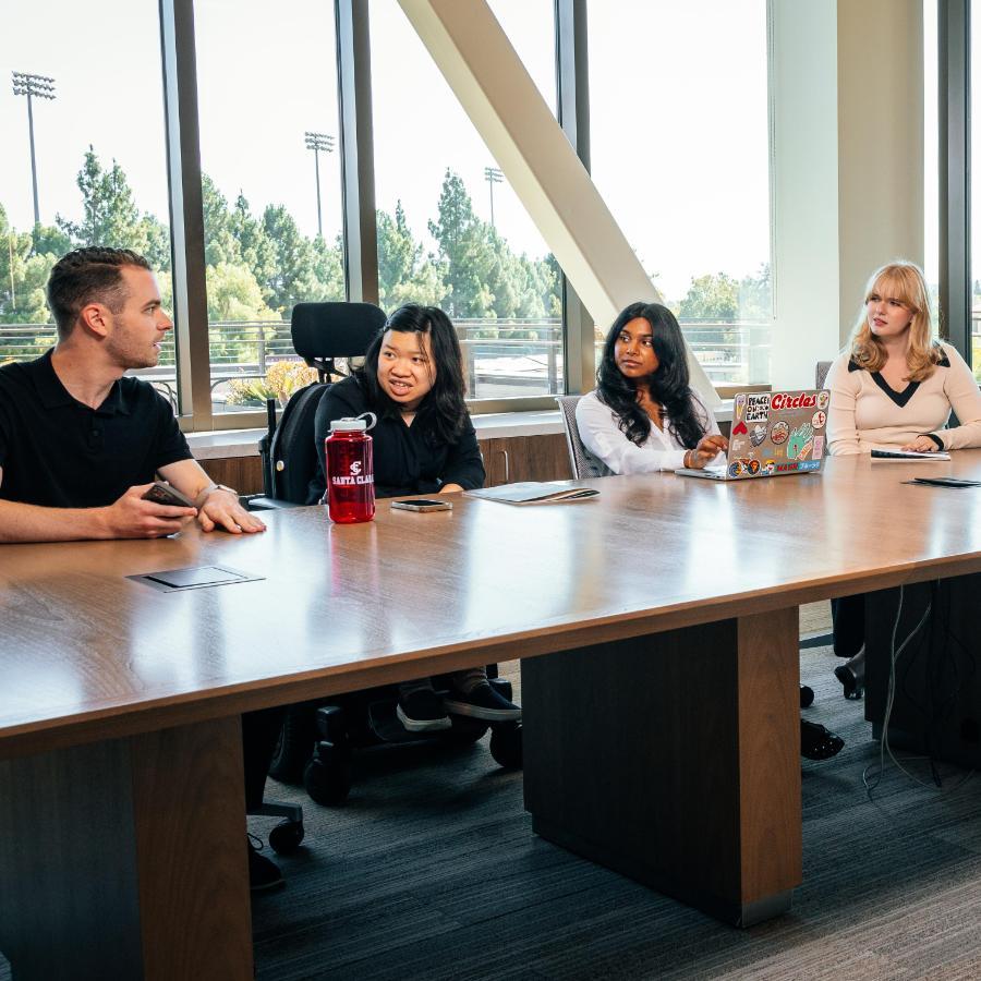 students at a conference table with faculty 
