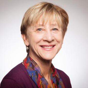 Smiling person wearing a scarf with light background. 