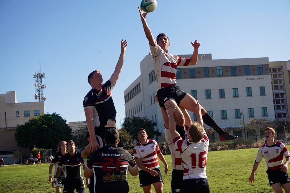 Men playing rugby, one player lifted to catch the ball.