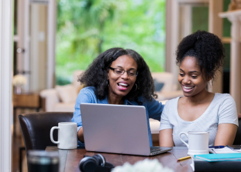 Parent and student looking at laptop on dining table 