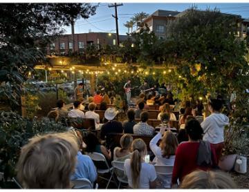 Students and people enjoying concert under string lights at the forge garden
