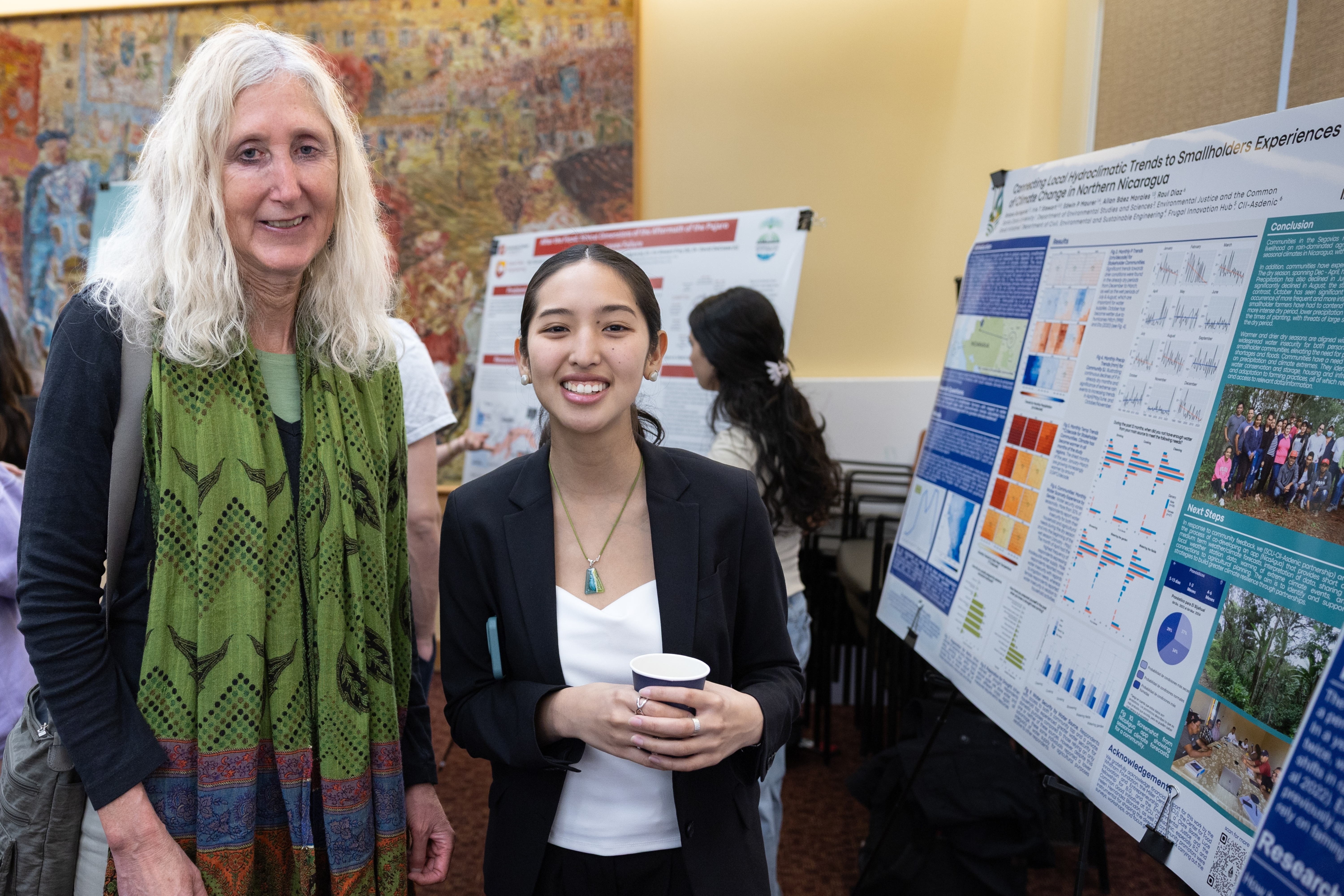 A faculty member and student stand in front of the latters research poster on hydroclimatic trends during the 2025 Sustainability and EJ Symposium.