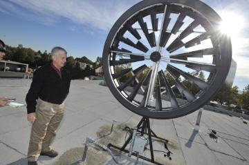 A person standing next to a wind turbine model.