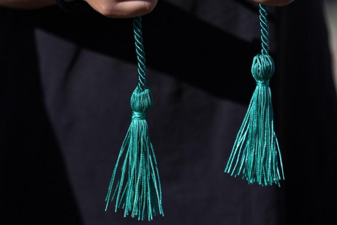 A student holding a green sustainability graduation cord in front of them