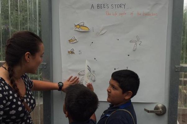 SCU student in greenhouse teaching kids about A Bee Story