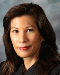 A woman with a neutral expression against a grey background. image link to story