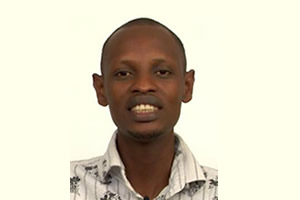 Person smiling in front of a plain background. image link to story