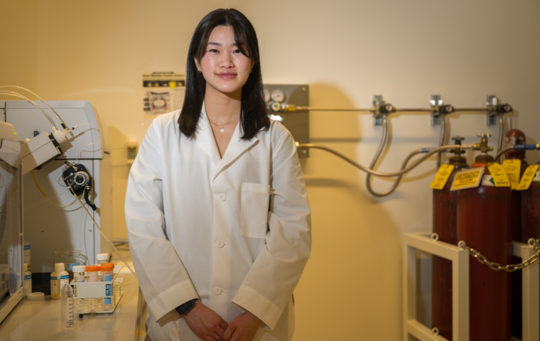 Samantha Lei, a young asian woman wearing a white lab coat looks to the camera, photo by Nic Coury