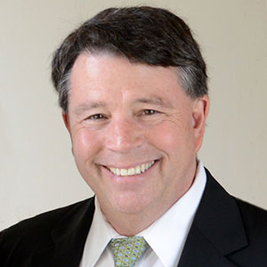 A man in a suit and tie smiling at the camera.