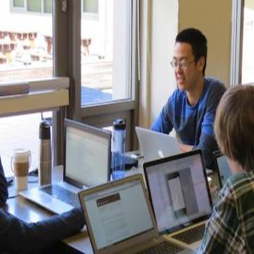 People working on laptops together in a room during a hackathon.