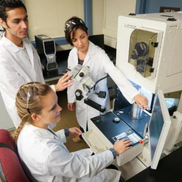 Three scientists working with laboratory equipment in a lab.