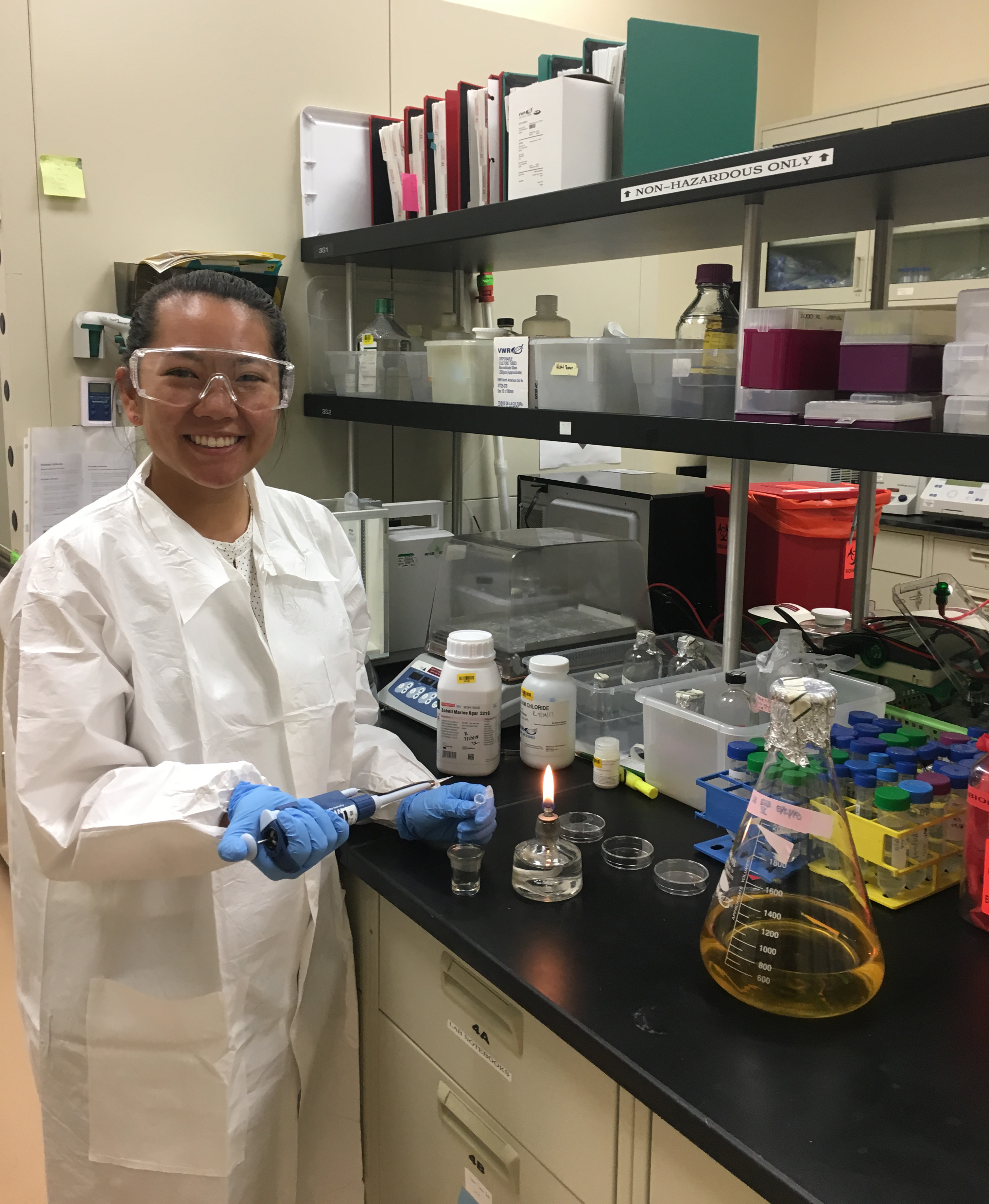 Person in a laboratory holding blue gloves and a beaker in Goo Portrait. image link to story